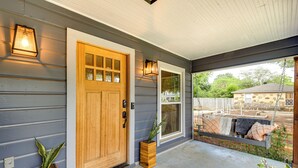 A wooden front door with a glass panel, a porch with a swing seat, and two potted plants. - Pecan Blue Frisco Hub: Dtwn, Dining & Stadiums! (Frisco)