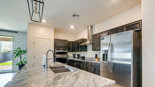 A modern kitchen with granite countertops, stainless steel appliances, and dark cabinetry. - Sunny Arizona Escape w/ Patio, Grill & Fireplace! (Glendale)