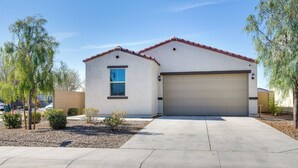 A single-story house with a garage, surrounded by a gravel driveway and small trees. - Sunny Arizona Escape w/ Patio, Grill & Fireplace! (Glendale)