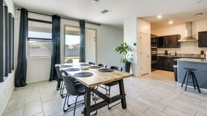 A modern kitchen with dark cabinets, a wooden island, and a dining area with a large table and chairs. - Sunny Arizona Escape w/ Patio, Grill & Fireplace! (Glendale)