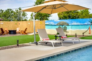 A poolside area with lounge chairs, a table, and an umbrella. - Glendale Getaway: Swim, Putt, Grill, & Relax! (Glendale)