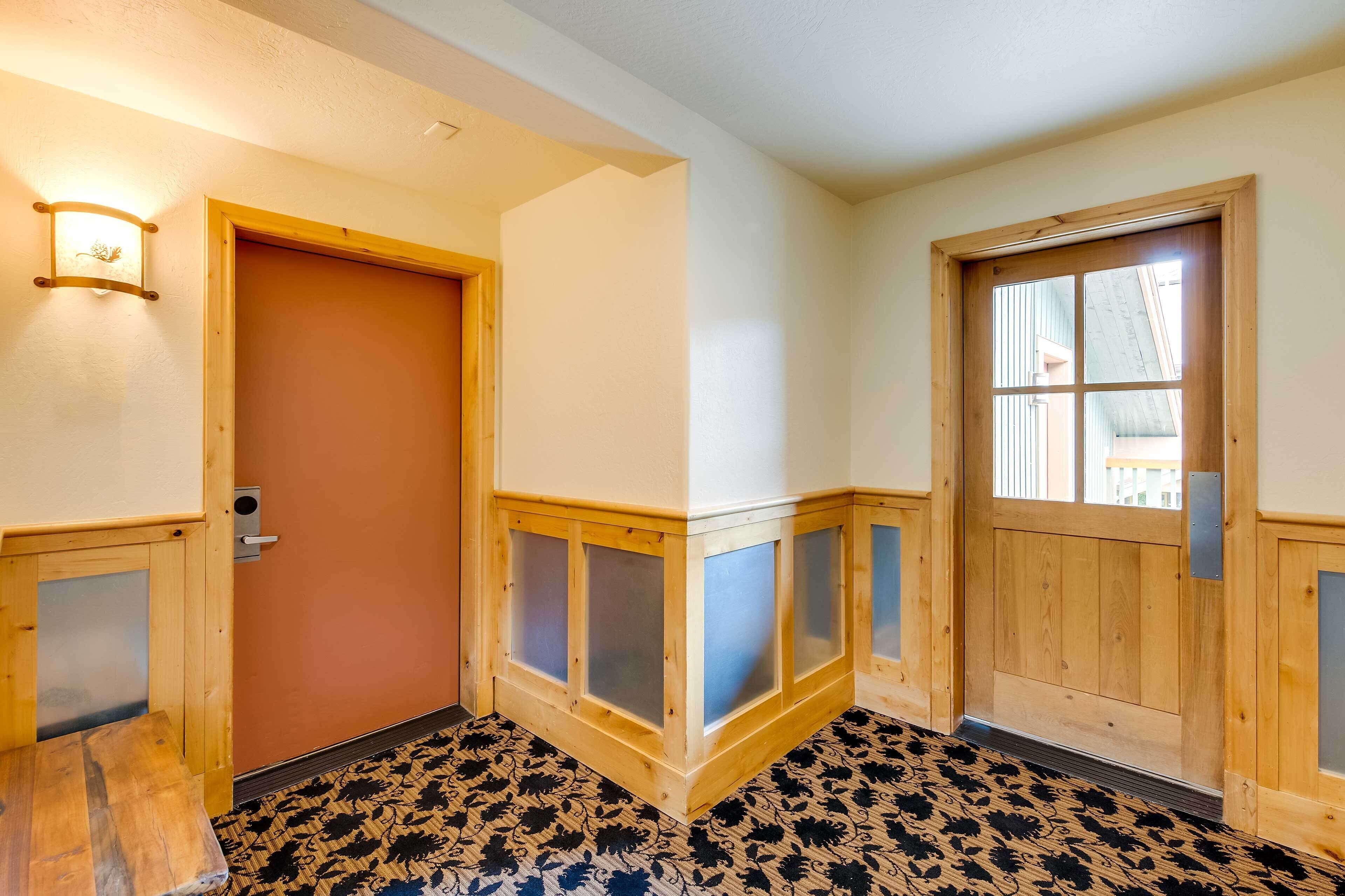 A hallway with wooden doors, a light fixture, and patterned flooring.