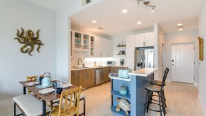 Una cocina moderna con armarios de madera, una isla central y un comedor con sillas y una mesa dispuesta para dos.