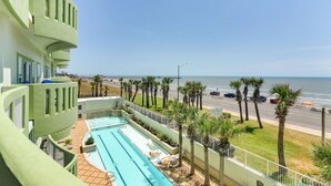 Un hotel con piscina, vistas a la playa y una carretera con coches.