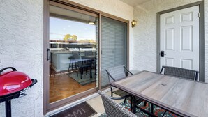 Un espace patio avec une porte-fenêtre coulissante, une table, des chaises et un barbecue.