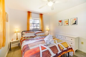 A neatly arranged bedroom with a bed, bedside lamps, a window with curtains, a ceiling fan, and wall art. - Family-friendly Home on Lake Tulane: Great Views! (Avon Park)