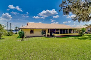 A single-story house with a large porch, a covered outdoor area, and a well-maintained lawn. - Family-friendly Home on Lake Tulane: Great Views! (Avon Park)
