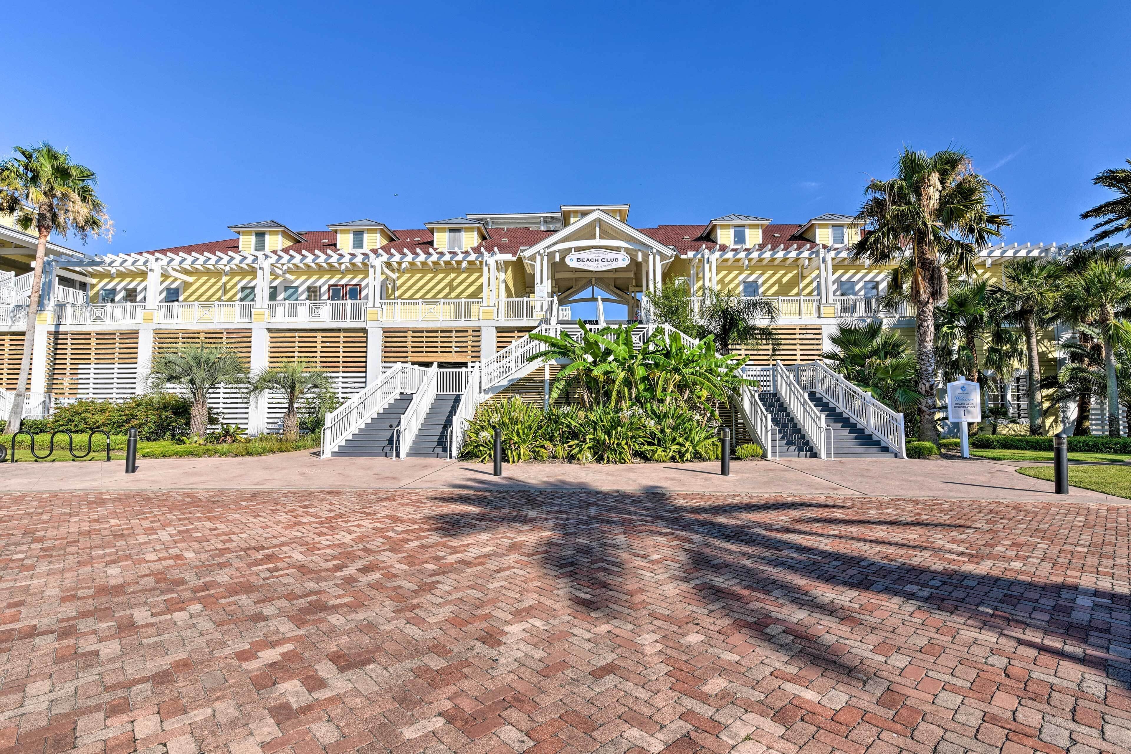 A beach club with a central staircase, palm trees, and a brick pathway.