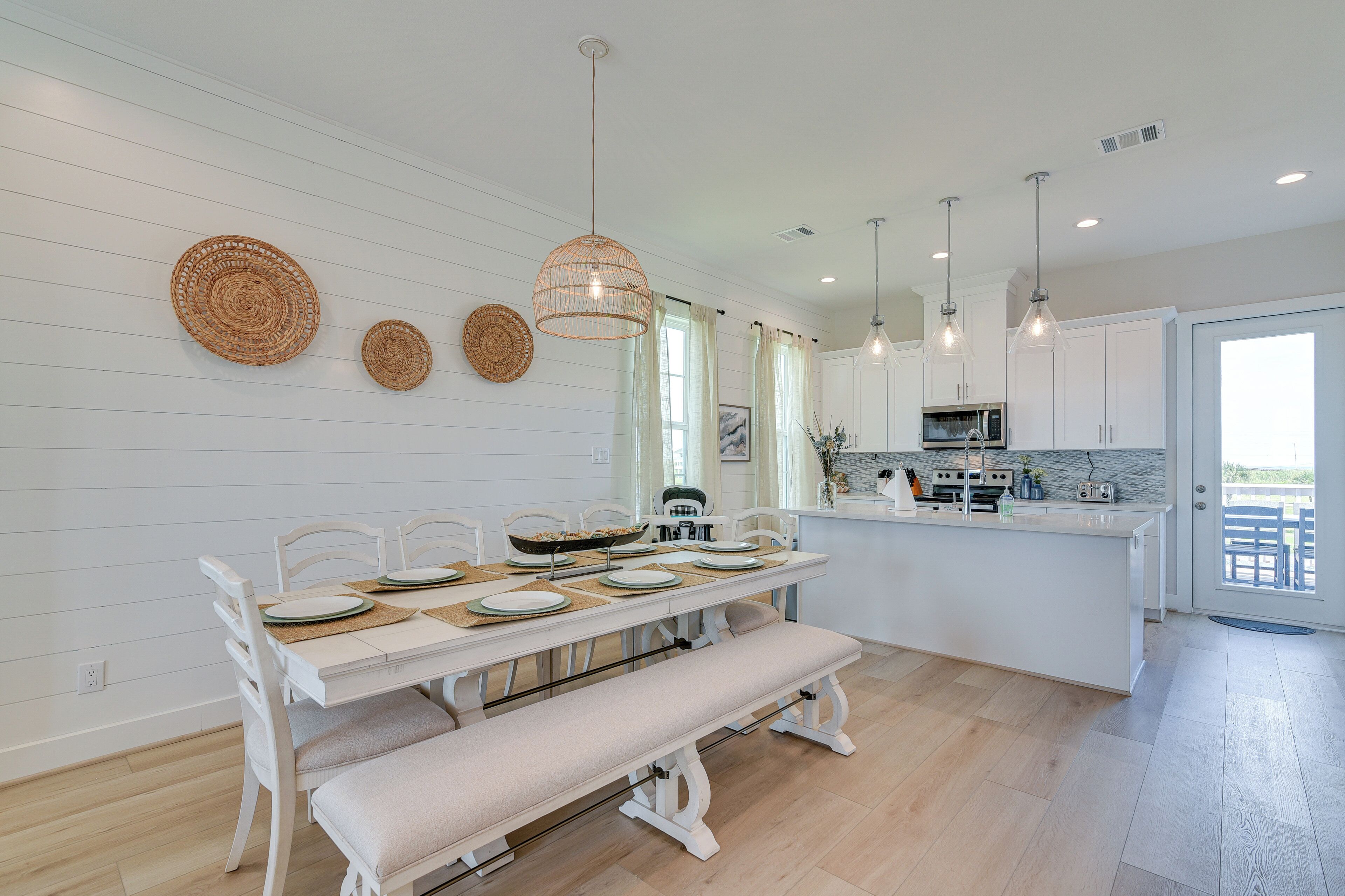 Una cocina moderna con armarios blancos, una isla central e iluminación colgante.
