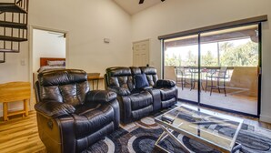 A spacious living area with a ceiling fan, a large sliding glass door leading to an outdoor patio, and a leather sofa. - Chandler Vacation Rental w/ Pool & Hot Tub Access (Chandler)
