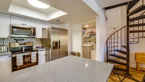 A modern kitchen with stainless steel appliances, a central island, and a spiral staircase. - Chandler Vacation Rental w/ Pool & Hot Tub Access (Chandler)