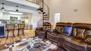 A spacious living room with a brown leather sofa, a wooden coffee table, and a spiral staircase leading to an upper level. - Chandler Vacation Rental w/ Pool & Hot Tub Access (Chandler)