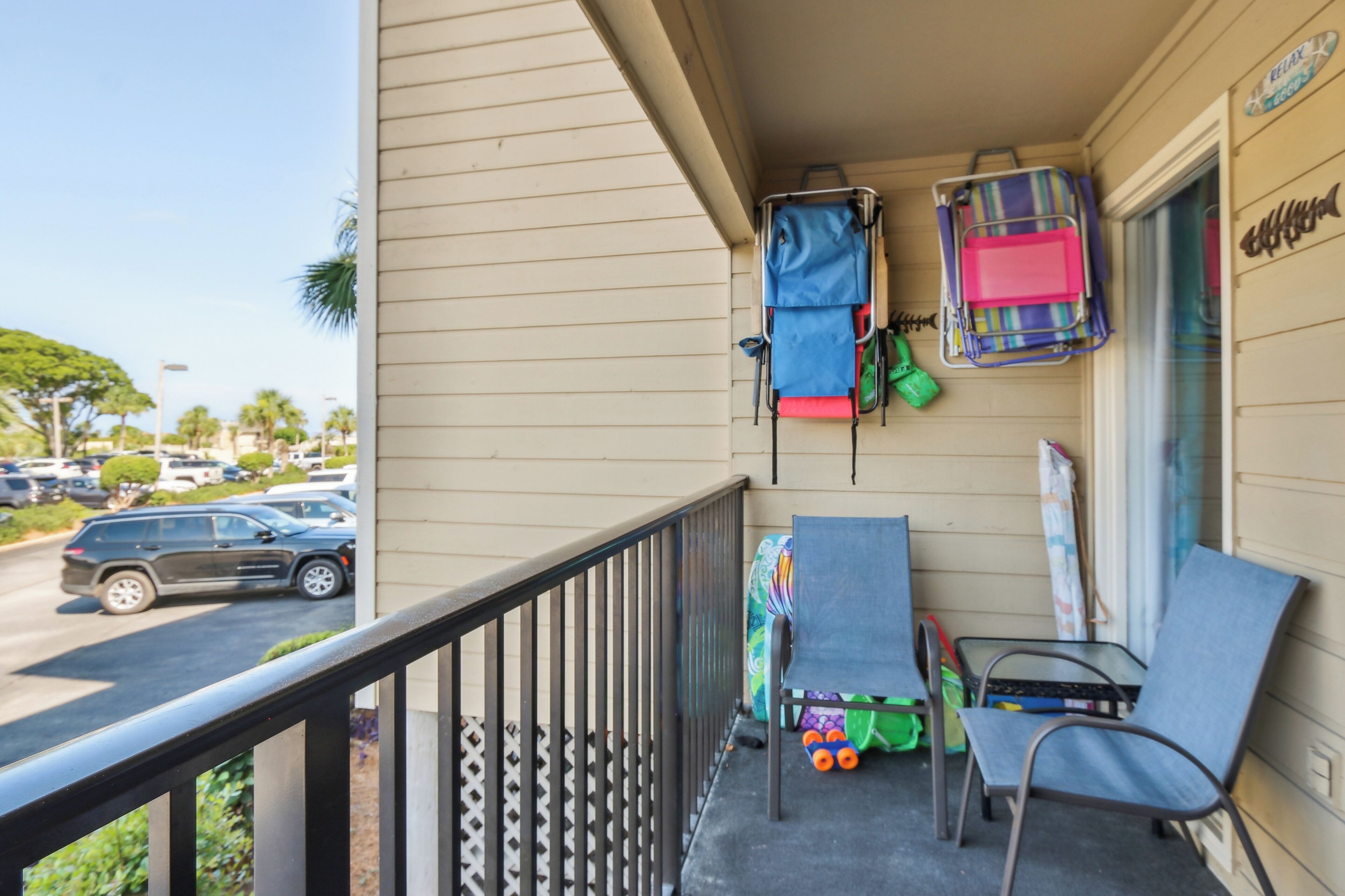 A balcony with a railing, a chair, a small table, and a suitcase.