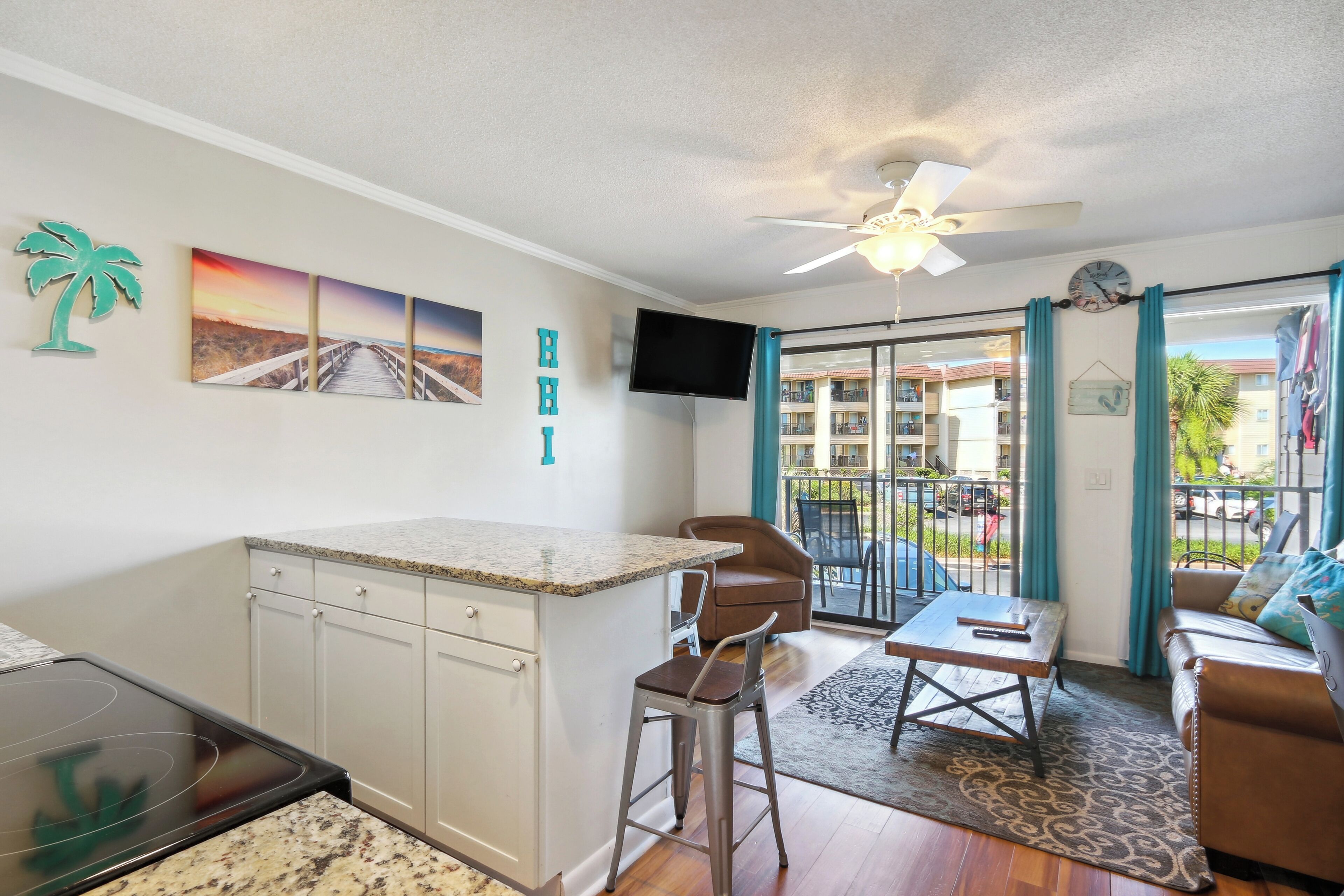 A compact living space with a kitchenette, a dining area, and a balcony with a view of the surroundings.