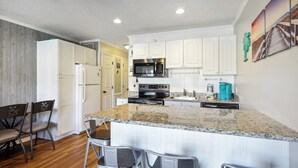 A modern kitchen with white cabinets, a granite countertop, and stainless steel appliances.