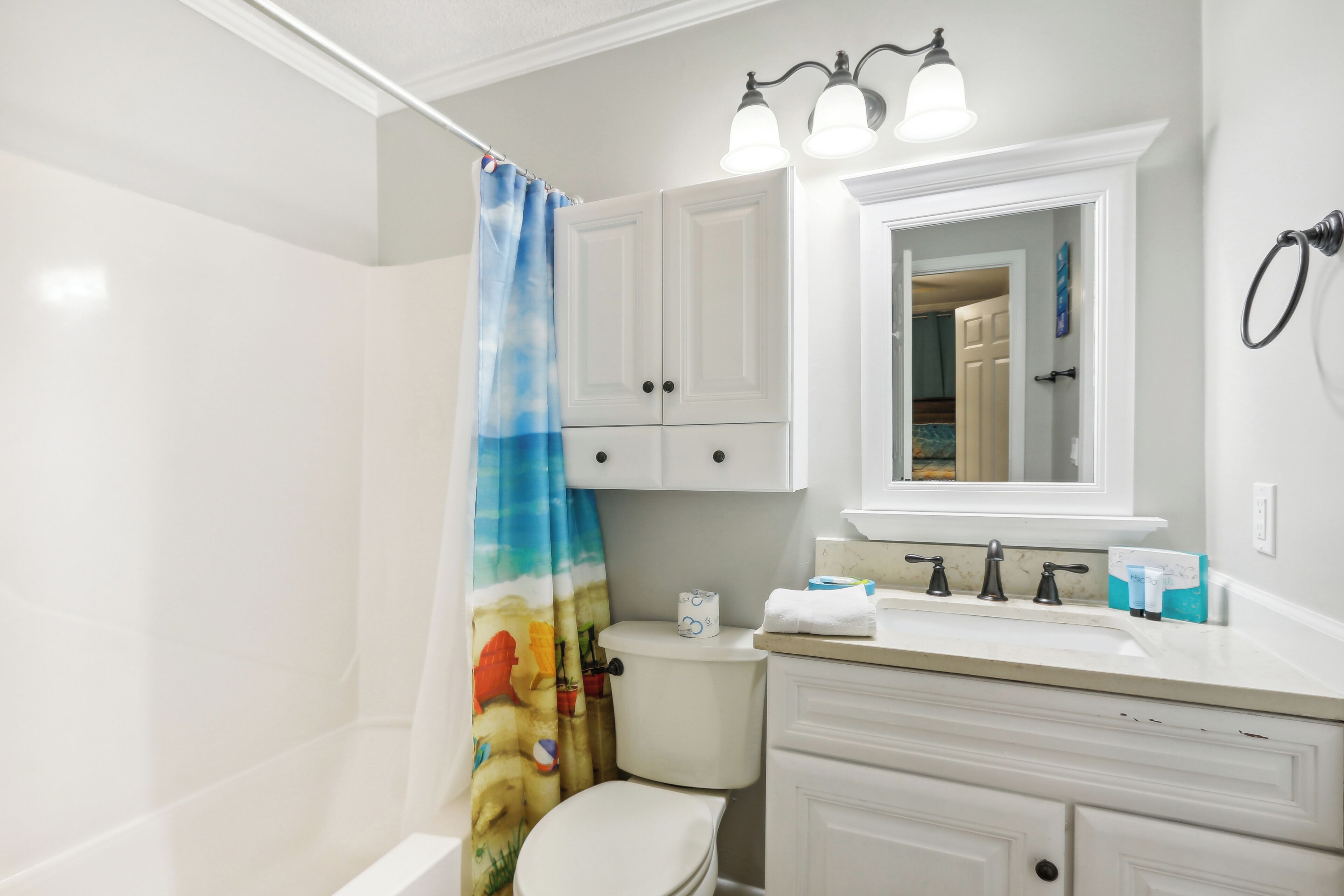 Une salle de bain avec des toilettes, un lavabo avec un miroir et un rideau de douche.