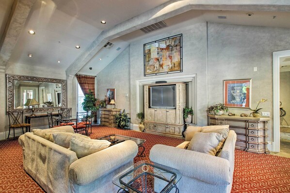 A spacious living room with high ceilings, a large TV, and comfortable seating.