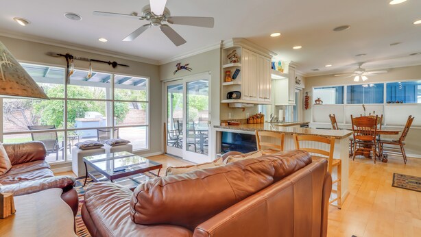 A spacious living room with a brown leather sofa, a glass coffee table, and a dining area with wooden chairs and a table.