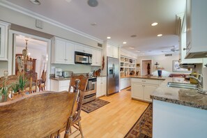 A spacious kitchen with white cabinetry, stainless steel appliances, and a wooden dining table. - Pool & Outdoor Kitchen: Home 10 Mi to Dtwn Phoenix (Phoenix)
