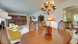 A dining area with a wooden table, wicker chairs, and a chandelier.