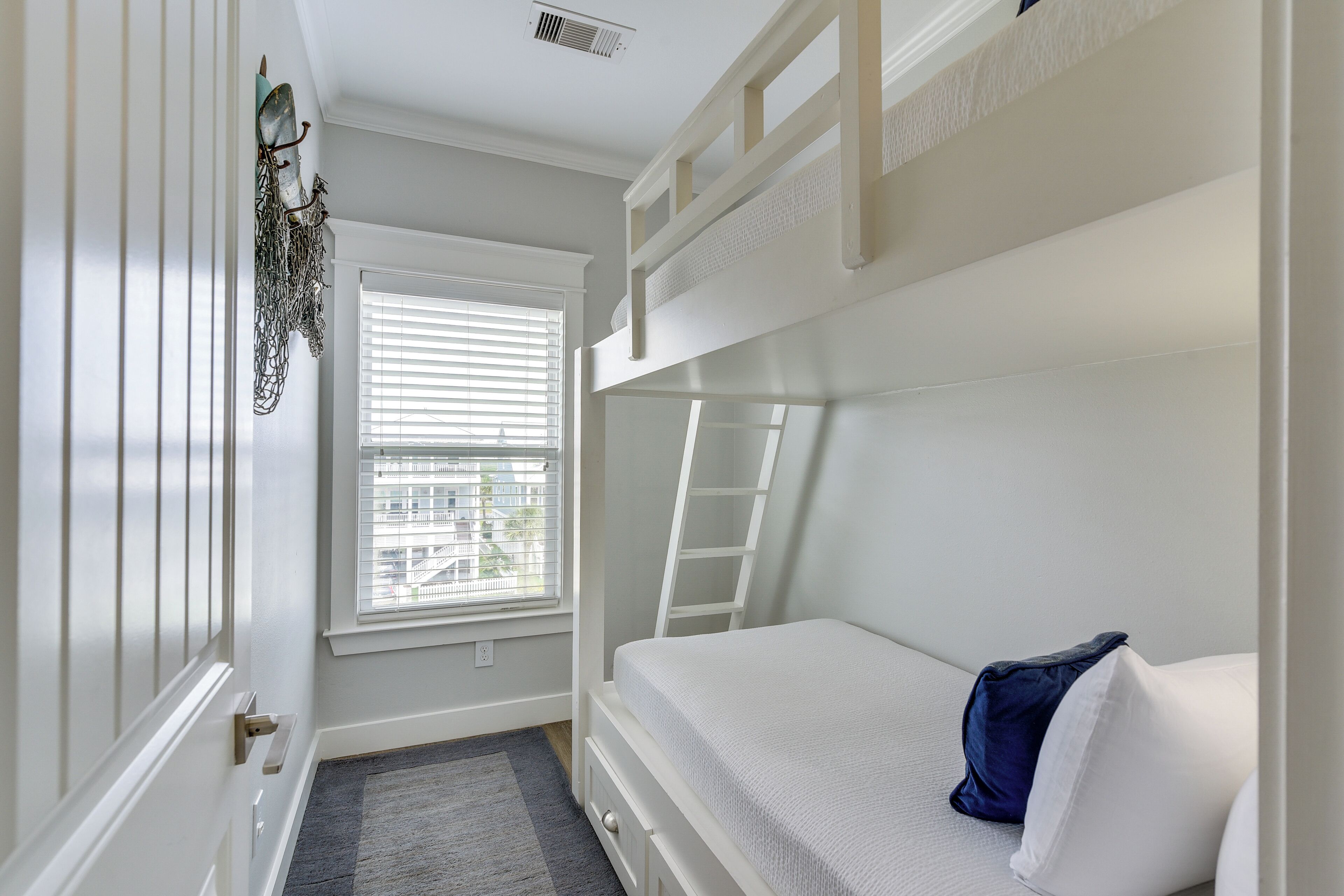 A bunk bed room with a window, a door, and a ladder.