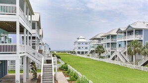A row of beachfront condominiums with multiple balconies, a well-maintained lawn, and a white picket fence. - Walk to Ocean! Group Beach House in Galveston (Galveston)