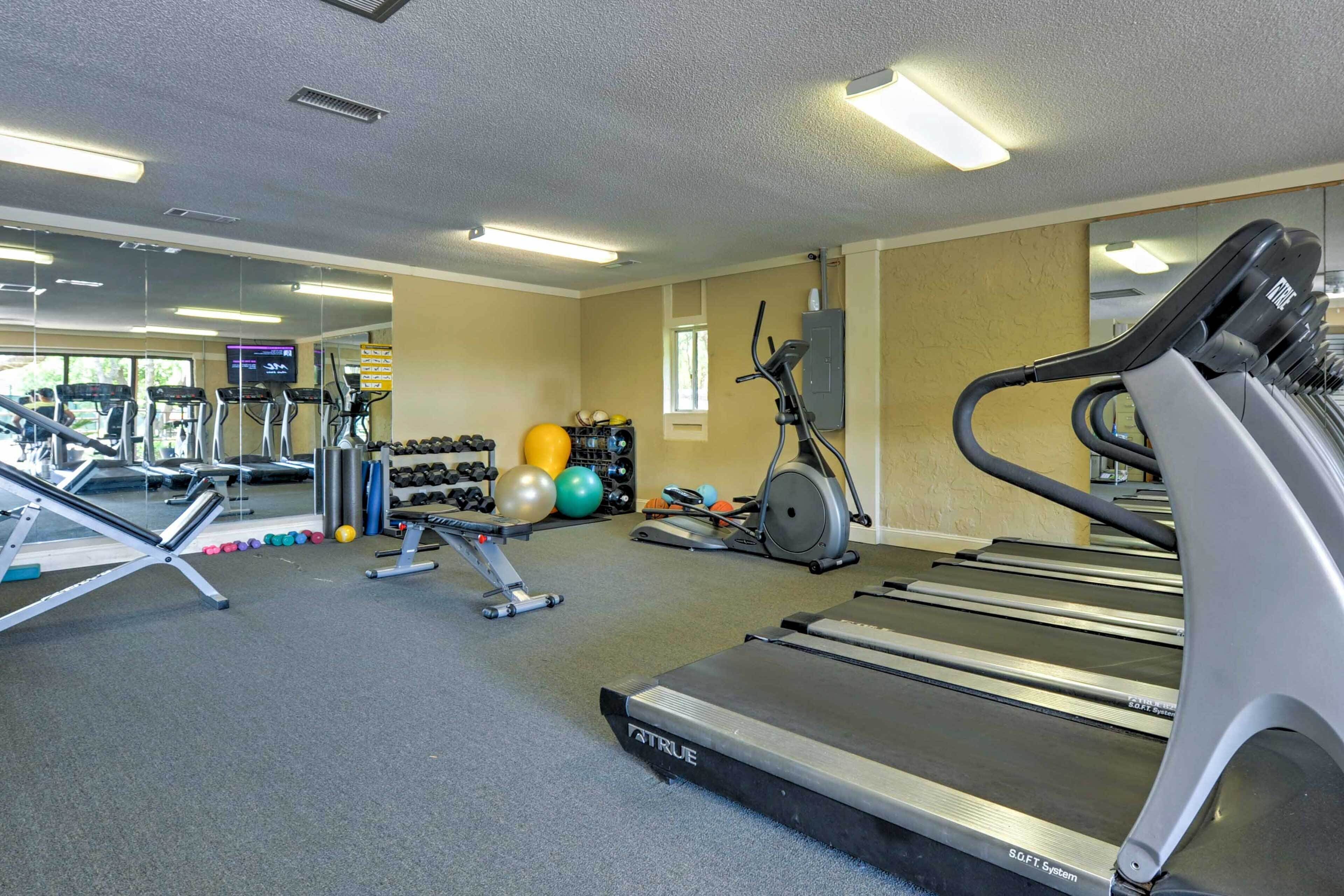 Une salle de sport équipée de tapis de course, d’haltères et de ballons d’exercice.
