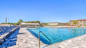 A swimming pool with sun loungers and a poolside area, surrounded by buildings and palm trees. - Top-floor Condo w/ Ocean Views in Hilton Head! (Hilton Head Island)