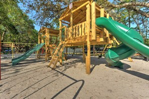 Ein Spielplatz mit Holzspielgeräten und grünen Rutschen.