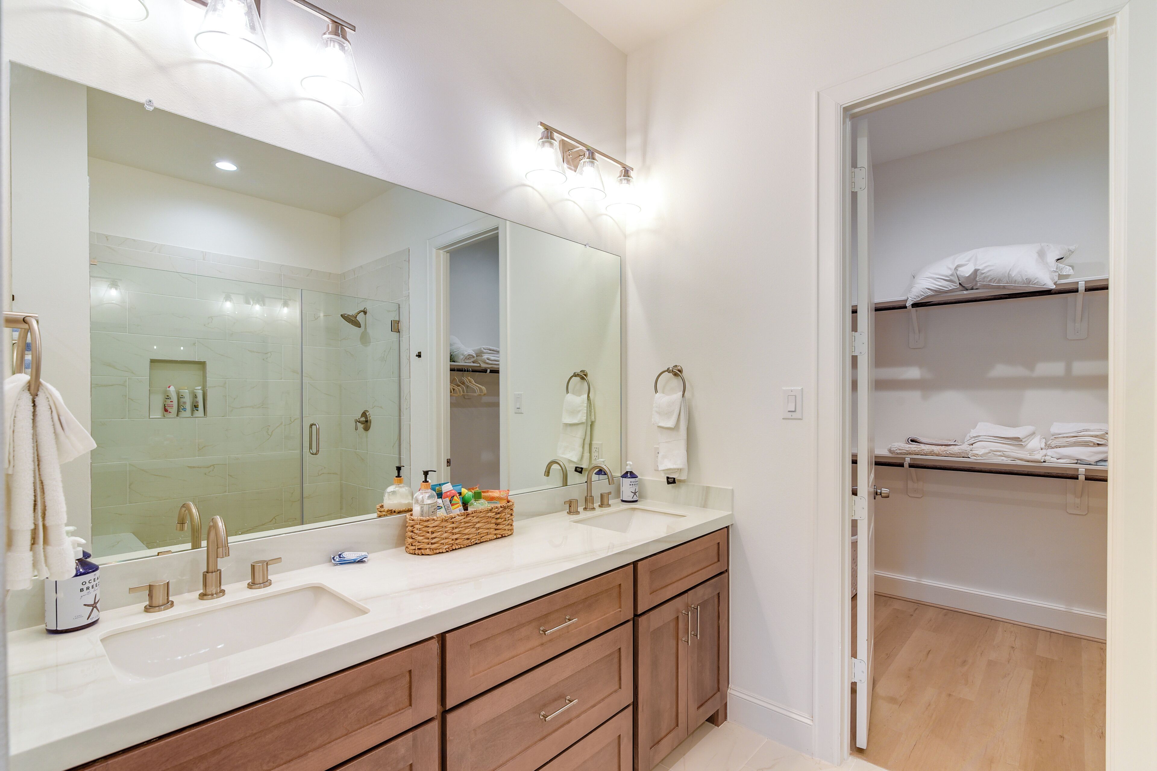 A bathroom with a large mirror, dual sinks, and wooden cabinets.