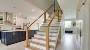 A modern kitchen with a central island, wooden staircase, and a view into the dining area. - Family-friendly Hilton Head Island Getaway w/ Deck (Hilton Head Island)
