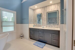 Un baño moderno con una bañera grande, un tocador doble y una ducha a pie.