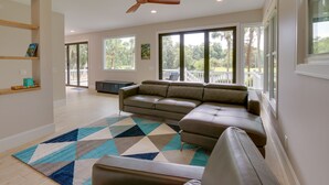 A spacious living room with a sectional sofa, a ceiling fan, and large windows offering a view of the outdoors. - Family-friendly Hilton Head Island Getaway w/ Deck (Hilton Head Island)