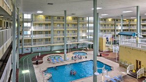 Ein mehrstöckiger, überdachter Poolbereich mit mehreren Balkonen, Liegestühlen und einer Poolterrasse.