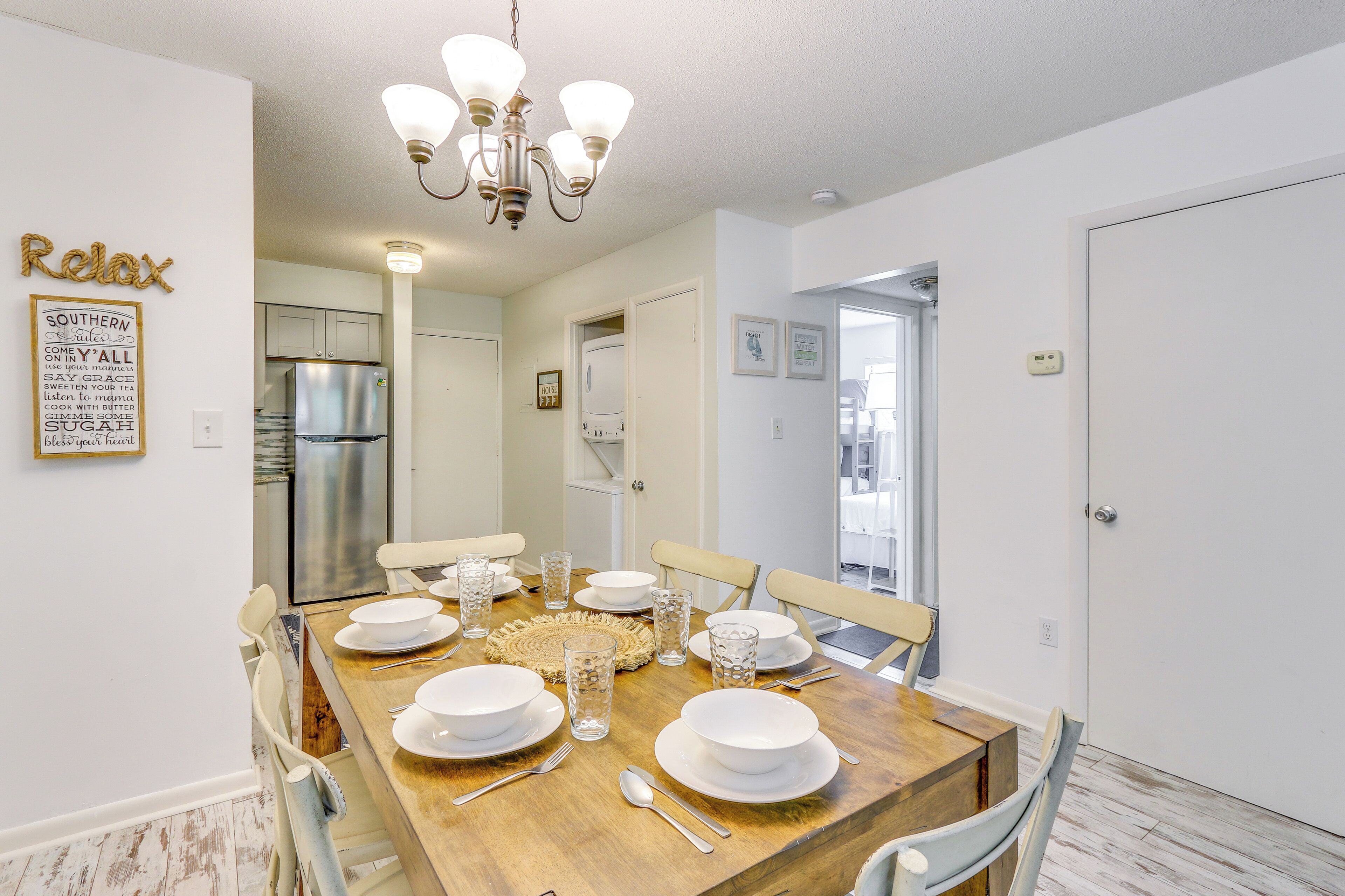A dining area with a wooden table set for four, white chairs, and a chandelier.