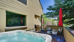 A hot tub on a wooden deck with outdoor chairs and an umbrella. - Deer Valley Retreat w/ Hot Tub & Movie Room (Park City)