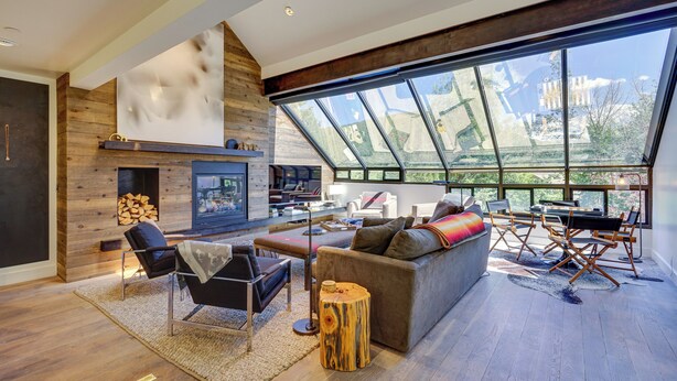 A spacious living room with a fireplace, comfortable seating, and large windows offering a view of the outdoors. - Deer Valley Retreat w/ Hot Tub & Movie Room (Park City)