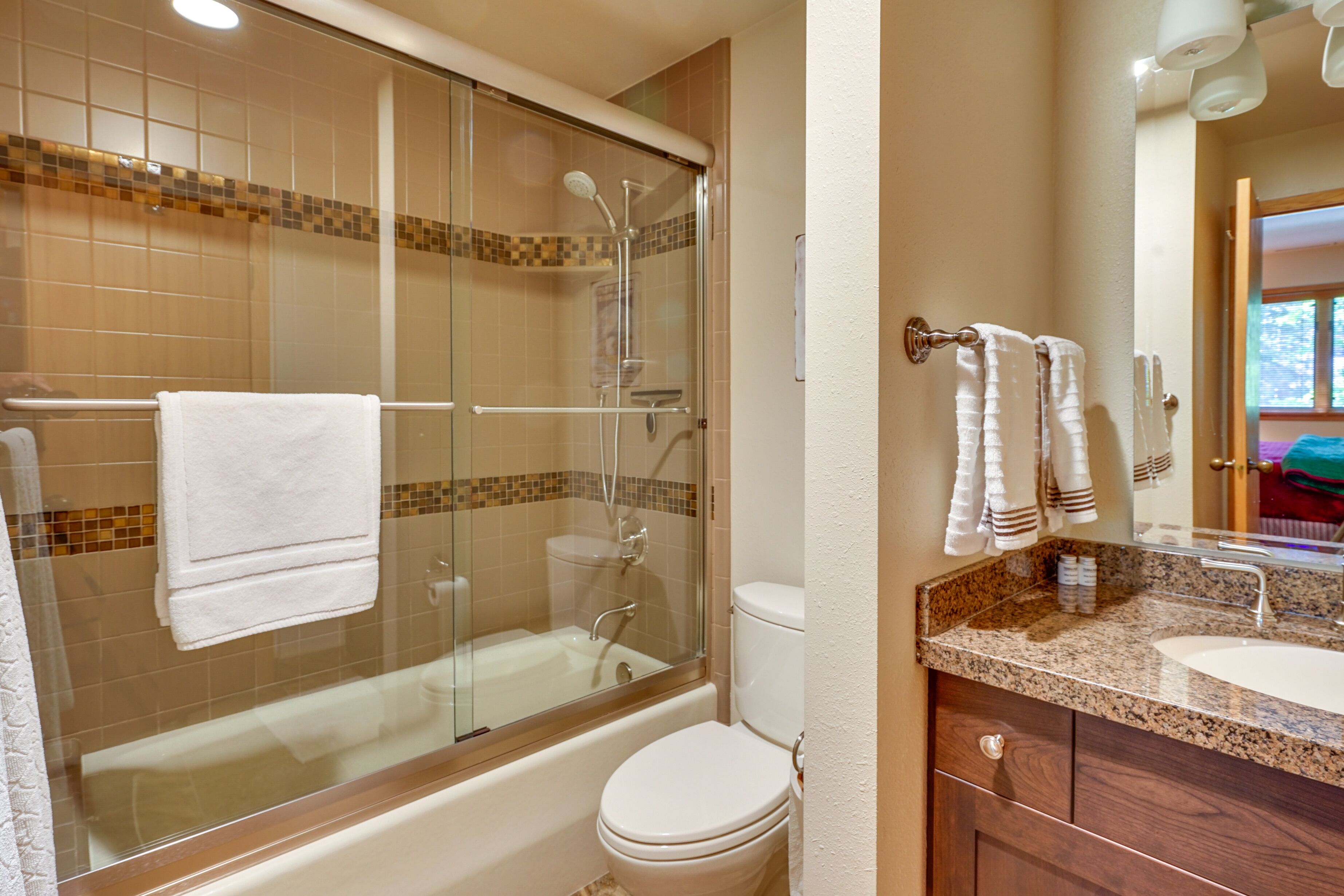A bathroom with a glass-enclosed shower, a bathtub, a toilet, and a vanity with a sink and mirror.