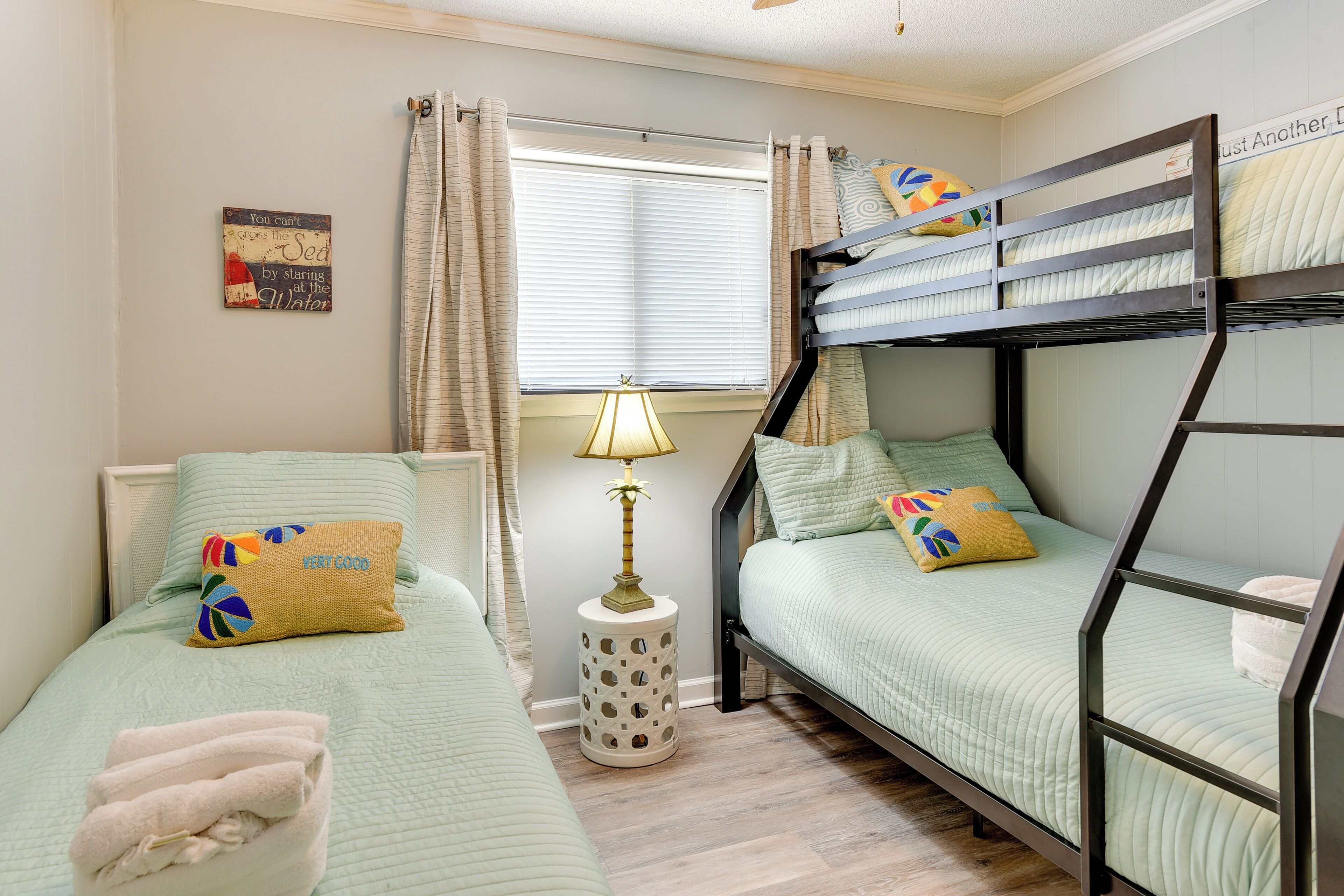 A room with bunk beds, a bedside lamp, a small round table, and a window with curtains.