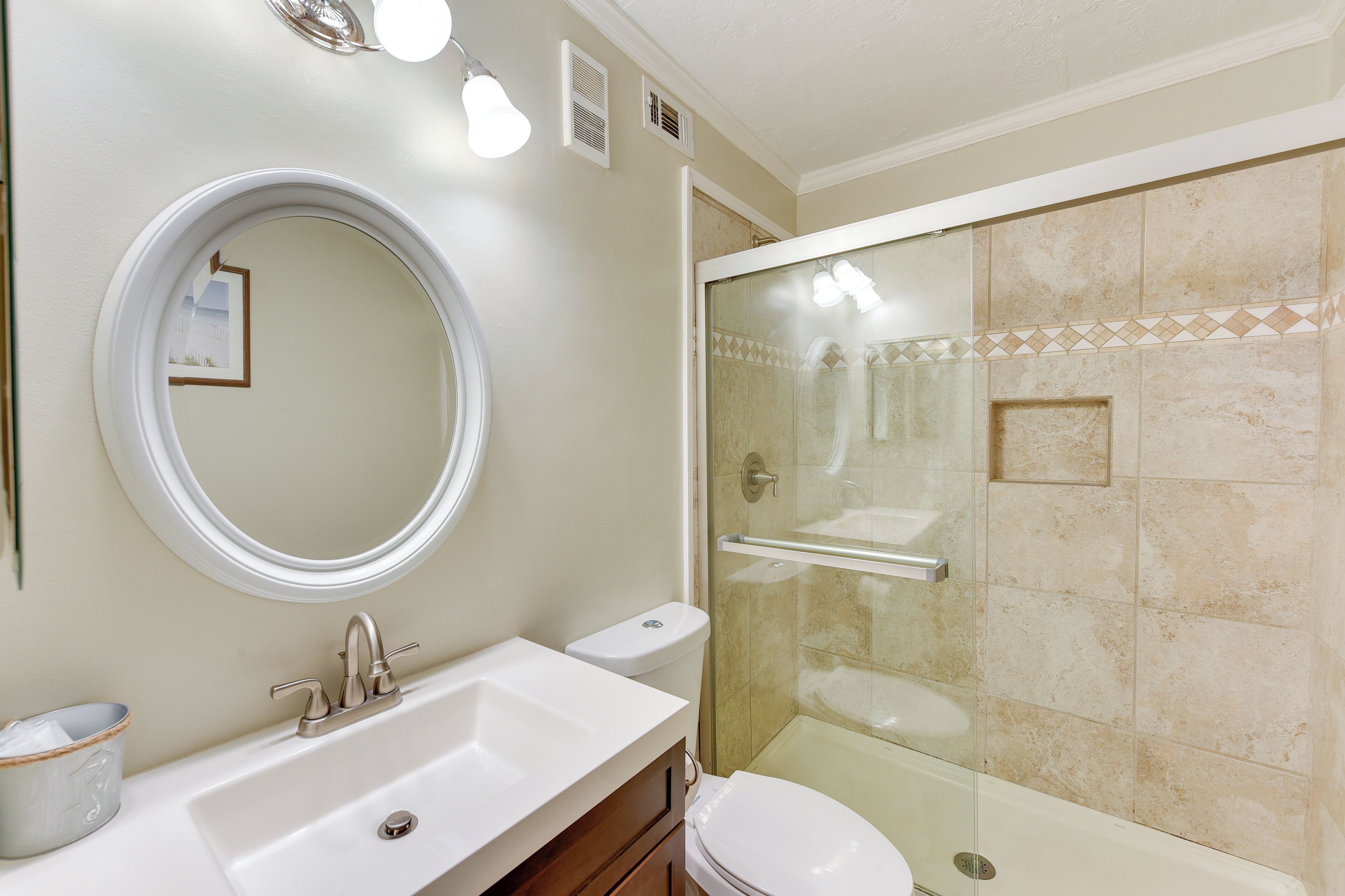 Un baño con lavamanos, inodoro y ducha con mampara de vidrio.