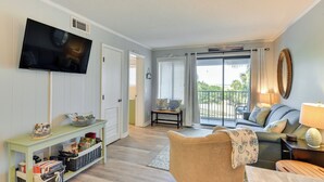 A living room with a television, a sofa, a chair, a console table, and a view of the outdoors through a sliding glass door. - < 1 Mi to Beach: Hilton Head Island Condo w/ Pool! (Hilton Head Island)