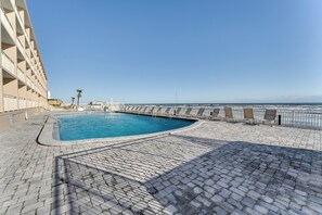 Une piscine à bord incurvé, entourée d’une allée pavée et d’une rambarde.