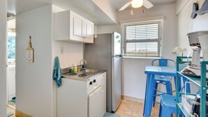 Une cuisine compacte avec des meubles blancs, une cuisinière encastrée, un réfrigérateur et une table bleue avec des chaises.