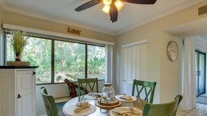 A dining area with a round table, green chairs, a ceiling fan, and a view of greenery outside. - Serene Hilton Head Island Condo w/ Community Pool! (Hilton Head Island)