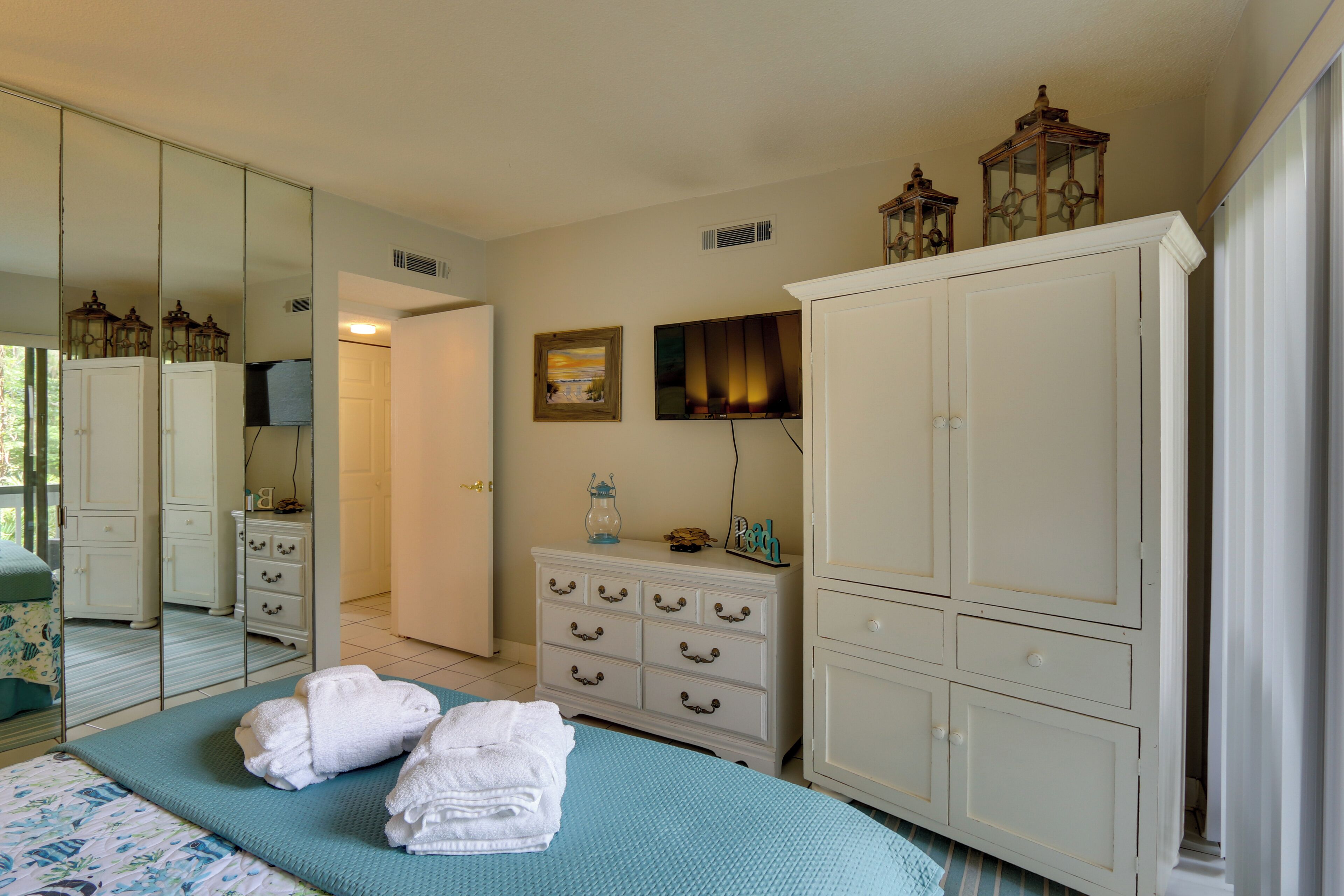 A bedroom with a bed, a dresser, a mirror, and a wardrobe.