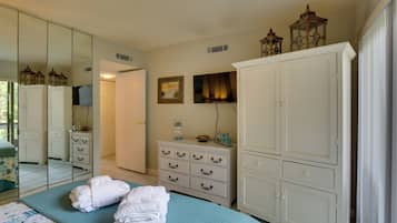 A bedroom with a bed, a dresser, a mirror, and a wardrobe.