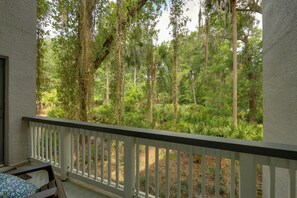 A balcony with a white railing overlooking a dense forest.