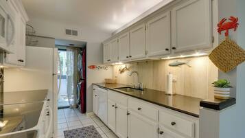 A modern kitchen with white cabinets, a black countertop, and a stainless steel sink.