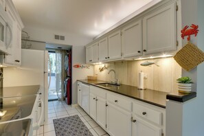 A modern kitchen with white cabinets, a black countertop, and a stainless steel sink.