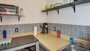 Une cuisine équipée d’un grille-pain, d’une machine à café et d’une étagère contenant de la vaisselle et une bouteille de liquide vaisselle.